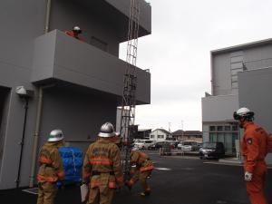 はしごを建物に立てかける様子