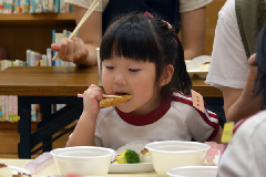 写真：魚のフライをおいしそうに食べる園児