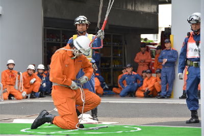 写真：仲間が見守る中はしご登はんの競技を行う消防士