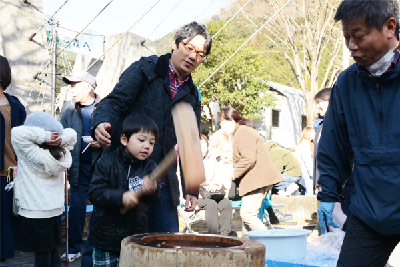 写真：杵（きね）と持ち餅つきする男の子と見守るお父さん