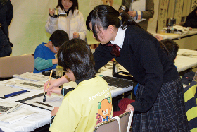 写真：えひめ子ども観光大使の小学生に習字を教える三島高校書道部員