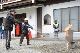 写真：消火器を使って炎を消す訓練に参加する寺参加者
