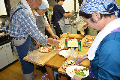 写真：ピザの生地に思い思いの具材を乗せる参加者たち