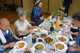 写真：焼きあがったピザと地元料理を楽しむ参加者たち