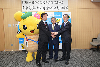 写真：協定書に署名後、市長、頭取、支店長で固く握手