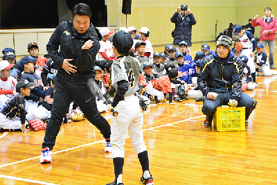 写真：児童に打撃のコーチをする岩村さん