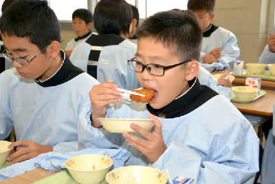 写真：地元産の鱧フライを食べる生徒たち