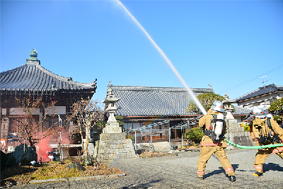 写真：本堂付近に向かって放水する消防署職員