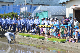 写真：先生からの説明を聞く高校生と園児たち