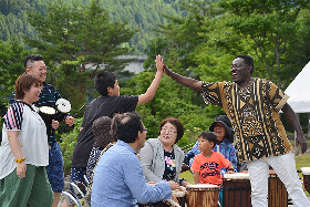 写真：アフリカの打楽器を体験し、指導者と喜びのハイタッチをする参加者