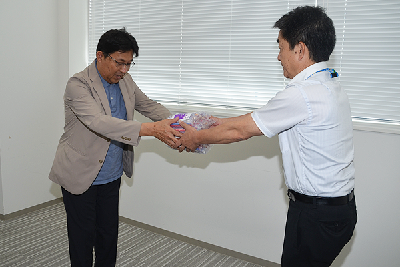 写真：歯ブラシを大西福祉部長に贈呈する野村会長