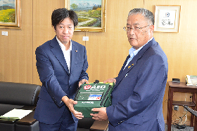 写真：福崎社長からAEDを手渡される篠原市長