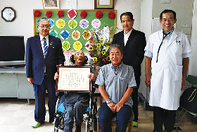 写真：男性最高齢者の尾藤さんを囲んで記念撮影