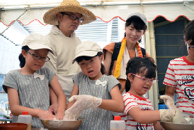 写真：地元の人に教えてもらいながらこんにゃくを丸める参加者たち