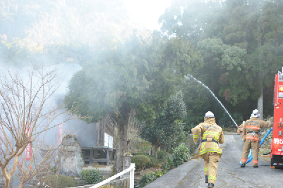 写真：本堂付近に向かって放水する消防署職員