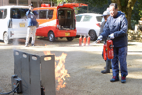 写真：消火器で消火訓練を行う参加者たち