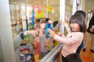 画像：ステンドカラーを窓に貼る子ども